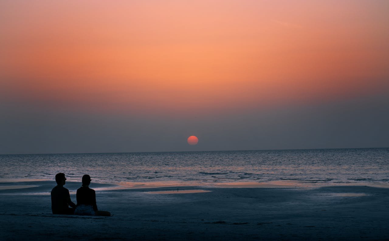 A serene sunset on Holbox beach, Mexico, with a couple enjoying the tranquil view.